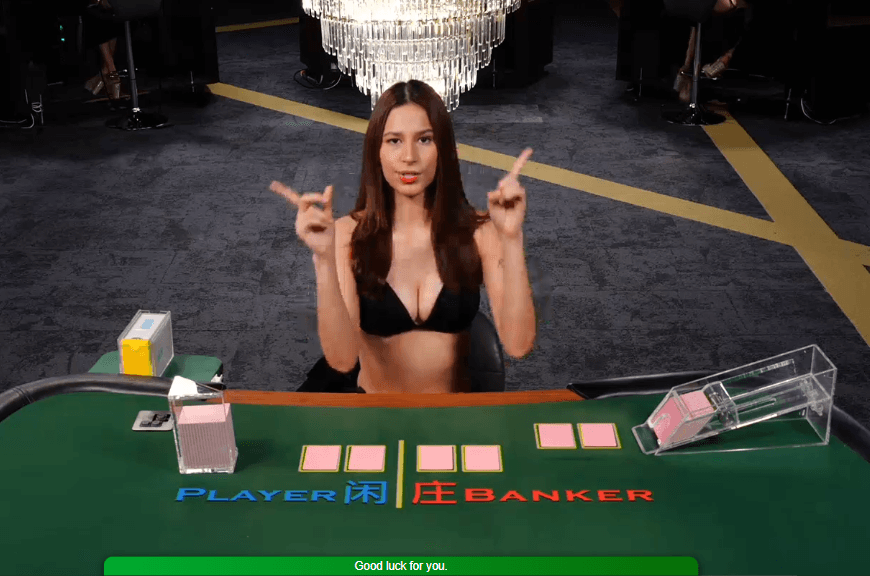 Woman in a black bikini top points upwards at a baccarat table with betting labels.